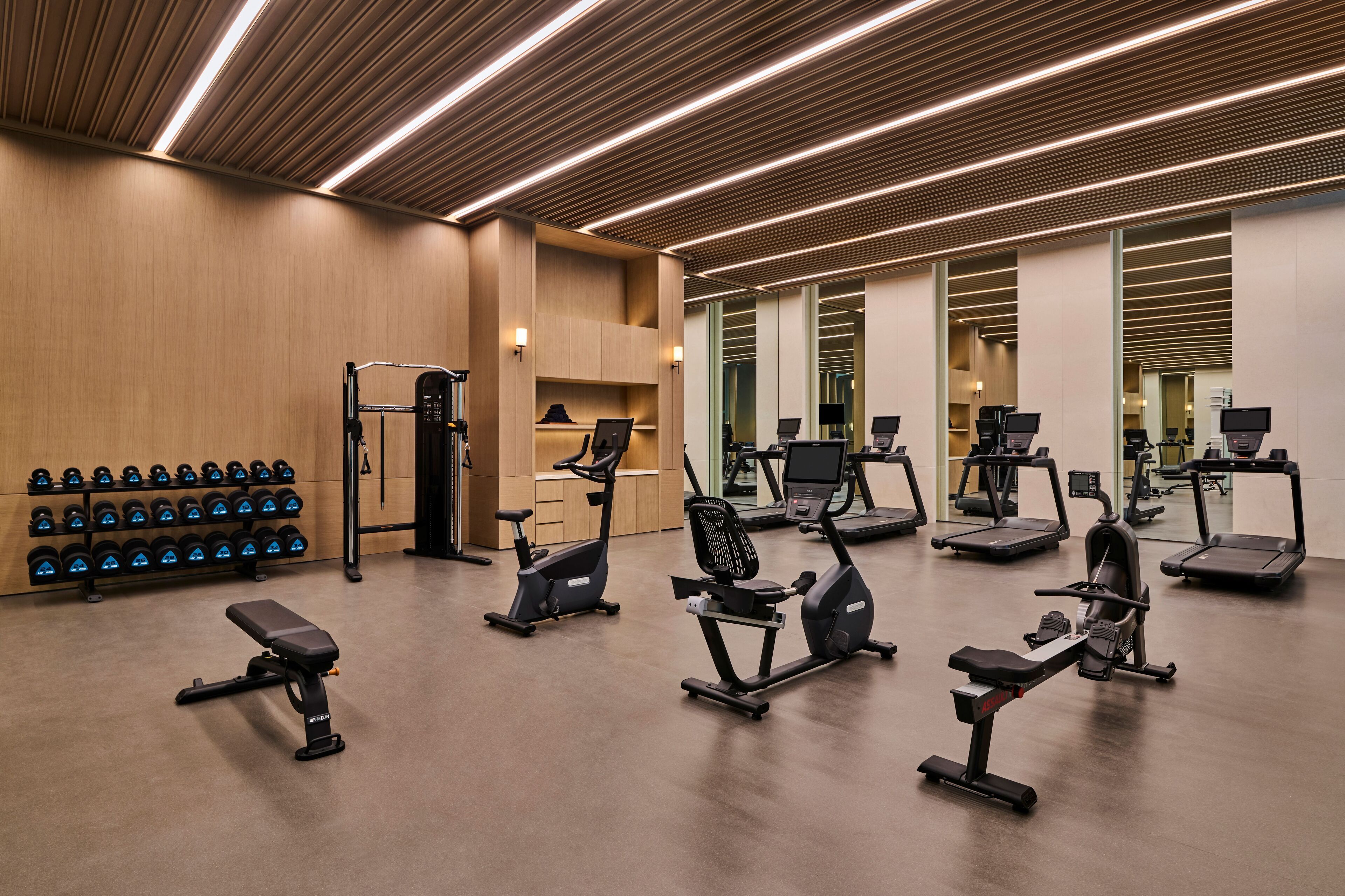 A modern gym with various exercise equipment, including treadmills, stationary bikes, and dumbbells.