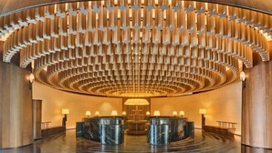 A lobby with a circular design, featuring a central light fixture and marble reception counters. - Shu Hua Hotel Tianmu Mountain, Curio Collection By Hilton (Hangzhou)