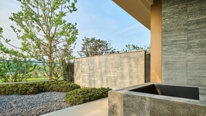 An outdoor area with a stone planter, a metal railing, and a view of greenery and hills. - Shu Hua Hotel Tianmu Mountain, Curio Collection By Hilton (Hangzhou)
