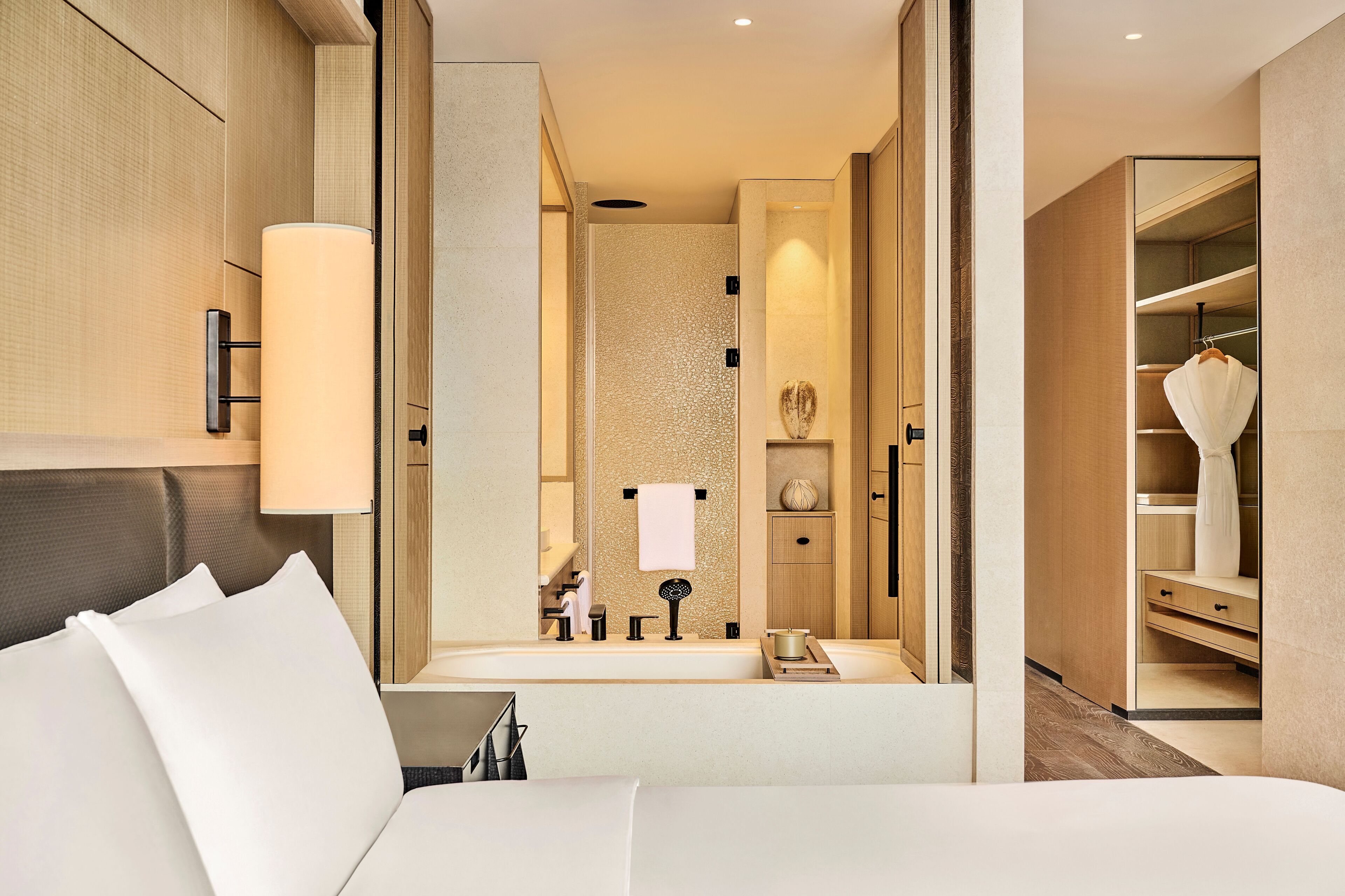 Una habitación de hotel moderna con una cama grande, un baño con bañera y un vestidor.