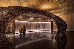 A modern interior with a unique arched ceiling design, a reflective floor, and a central light feature. - Shu Hua Hotel Tianmu Mountain, Curio Collection By Hilton (Hangzhou)