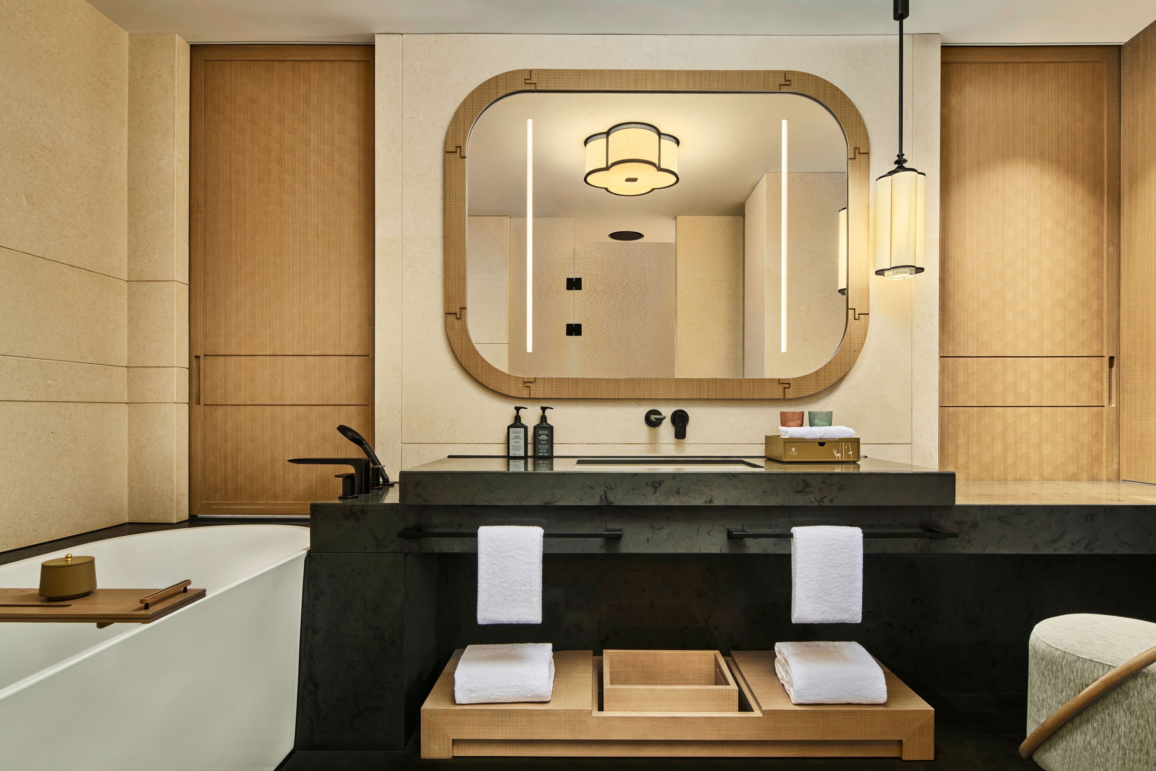 Un baño moderno con un espejo grande, tocador de madera y bañera.