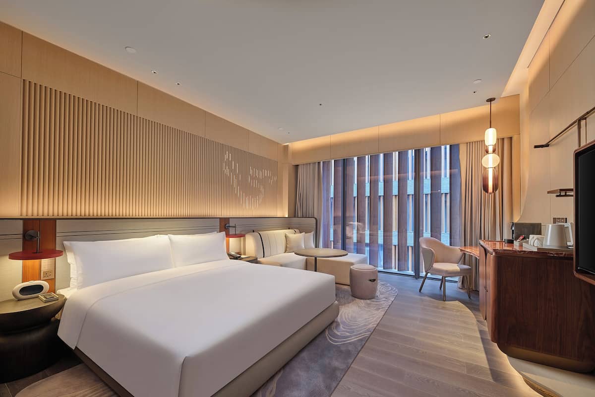Een moderne hotelkamer met een groot bed, een bureau, een stoel en een televisie.