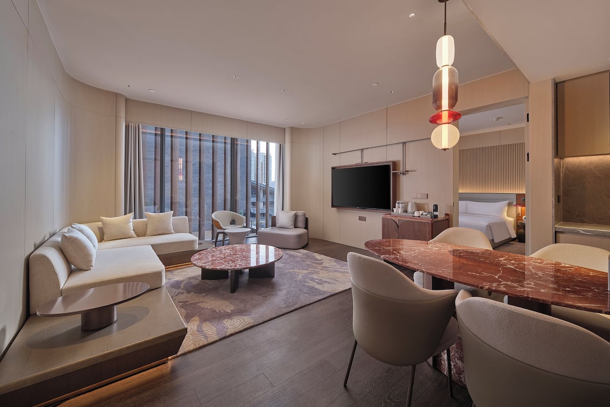 Een moderne woonkamer met een bank, stoelen, een salontafel, een televisie en een eethoek.