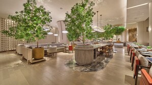 A spacious indoor area with seating arrangements, a central plant feature, and a modern ceiling design. - The Reserve Hotel Luoyang, Curio Collection By Hilton (Luoyang)