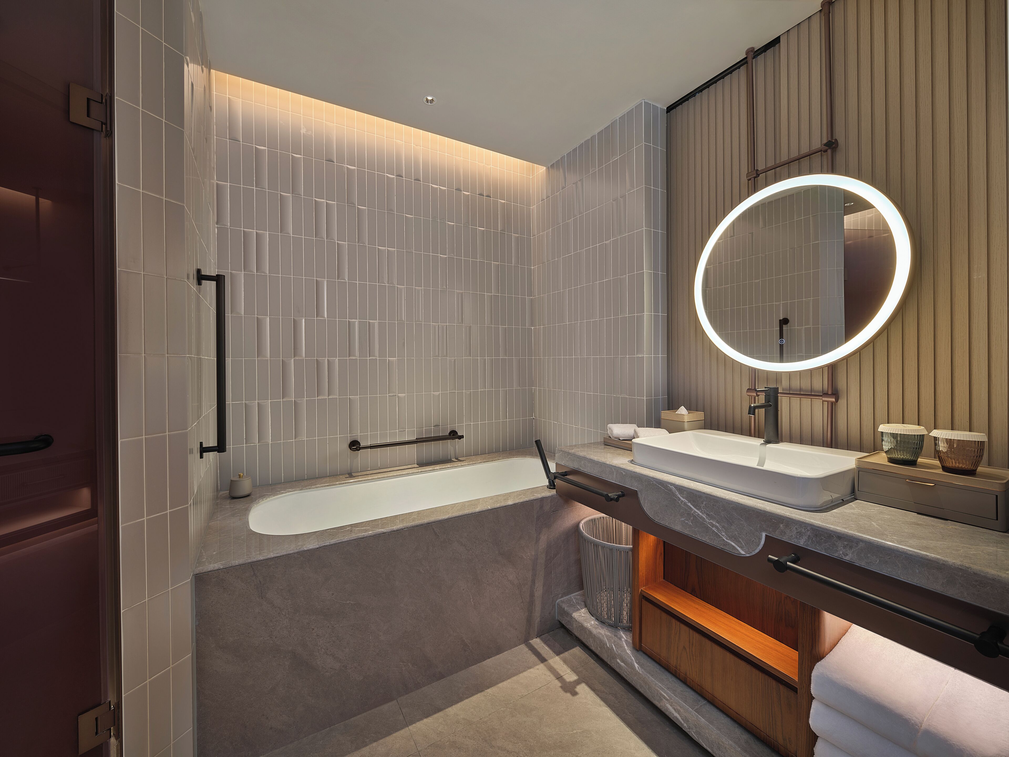 A modern bathroom with a bathtub, a vanity with a mirror, and a towel rack.
