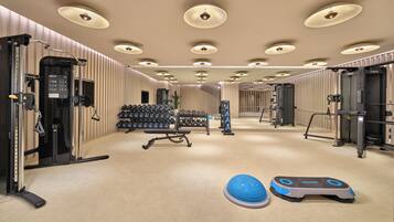 Un gimnasio con equipo de ejercicio, pesas y una pelota de ejercicios azul.