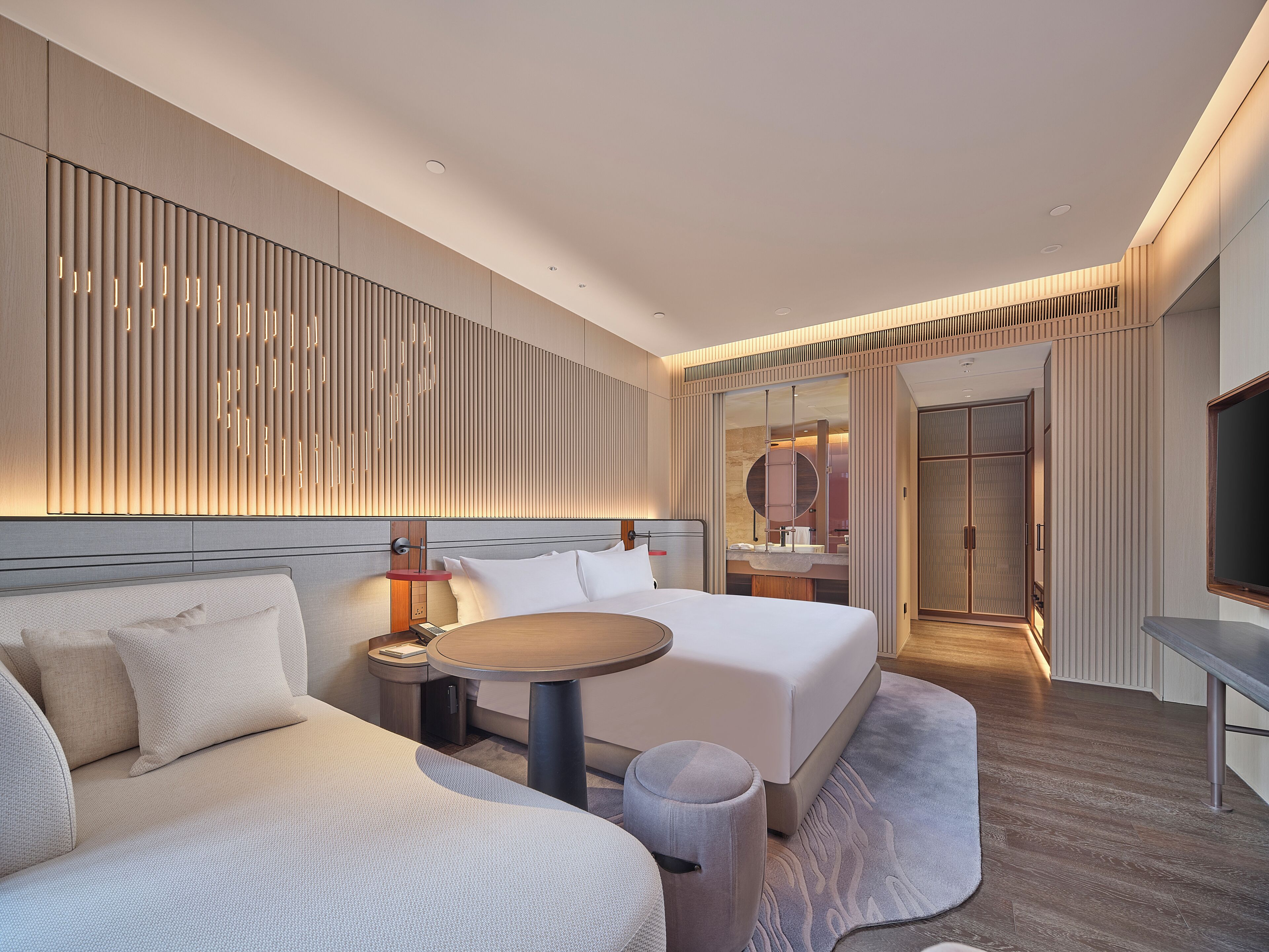 Een moderne hotelkamer met een bed, een bank, een klein tafeltje en een spiegel.