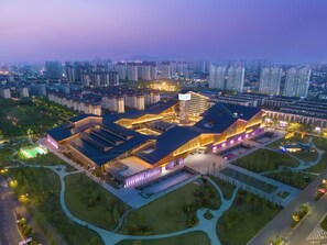 A modern building complex with multiple structures, surrounded by a landscaped area with pathways and greenery.