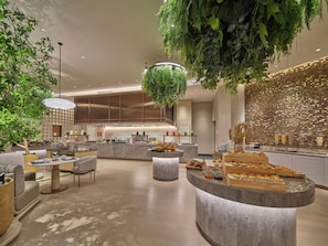 Un intérieur moderne avec un comptoir central, un espace salon et des plantes suspendues.