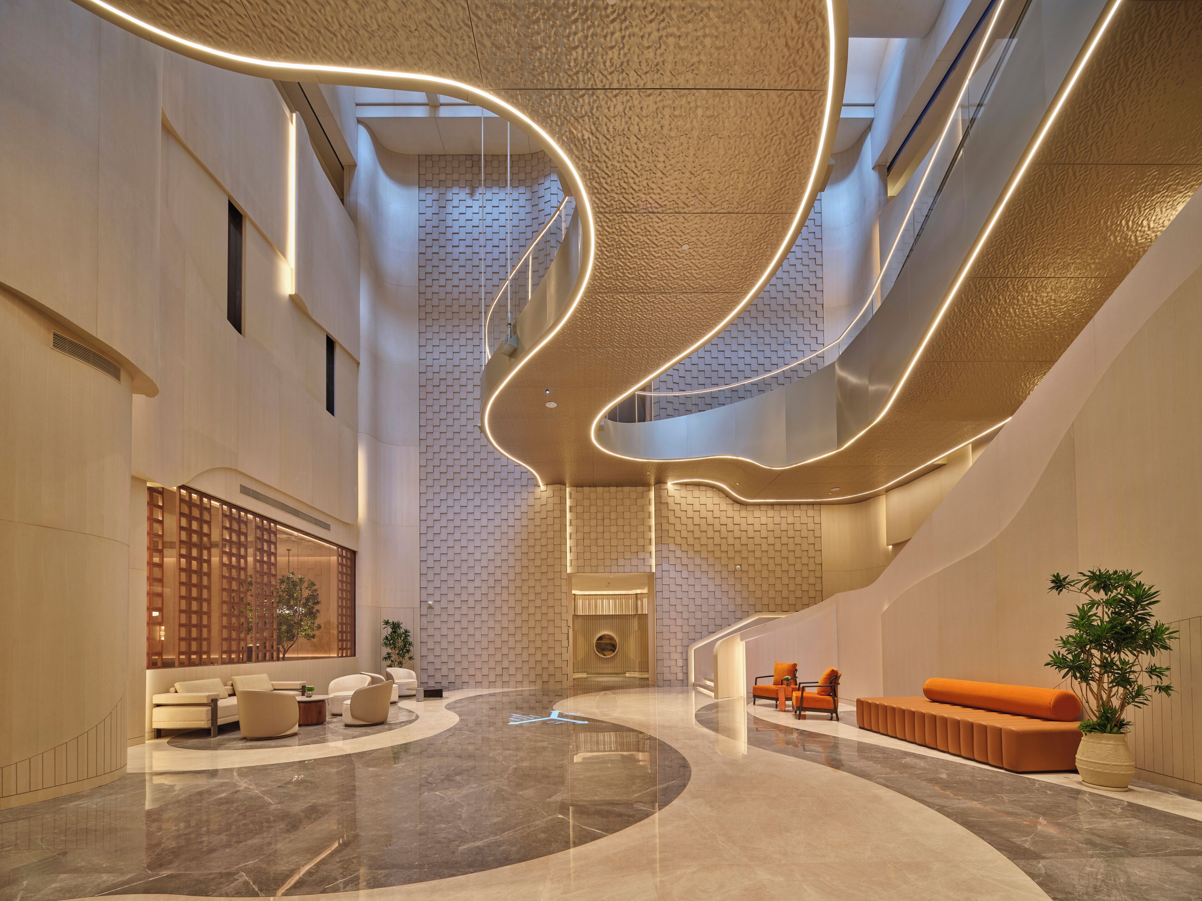 A modern lobby with a curved seating area, a reception desk, and a staircase.
