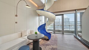 A modern interior with a white sofa, a round table with a vase, a blue chair, and a white spiral structure. - The Reserve Hotel Luoyang, Curio Collection By Hilton (Luoyang)