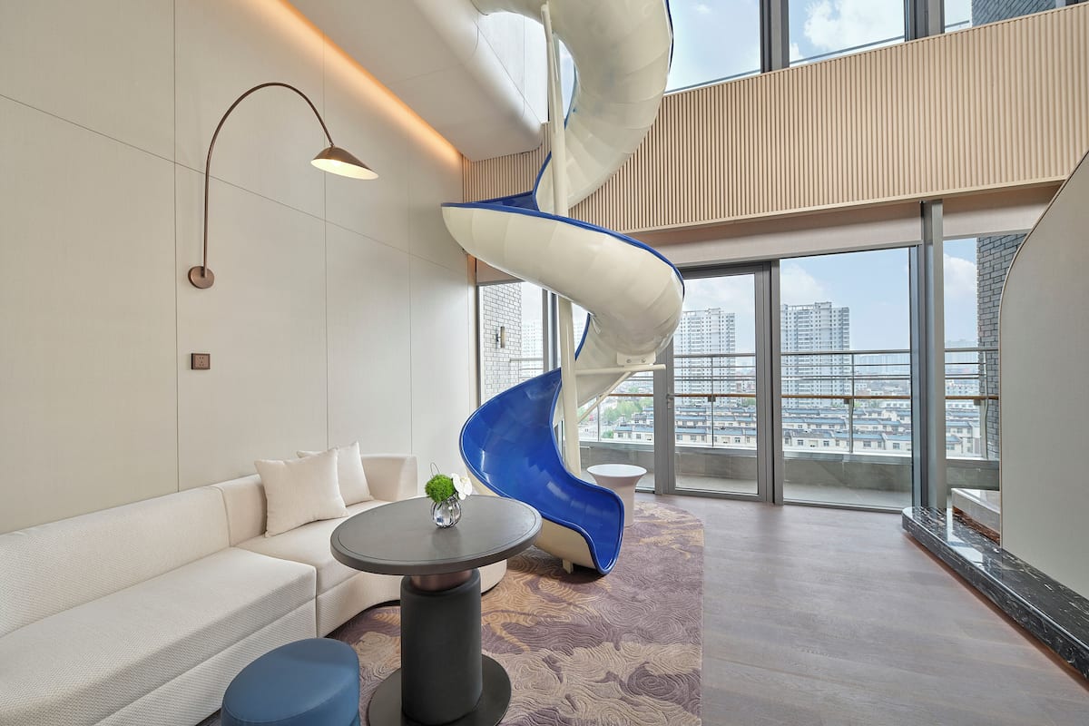 Een modern interieur met een witte bank, een ronde tafel met een vaas, een blauwe stoel en een witte spiraalvormige constructie.