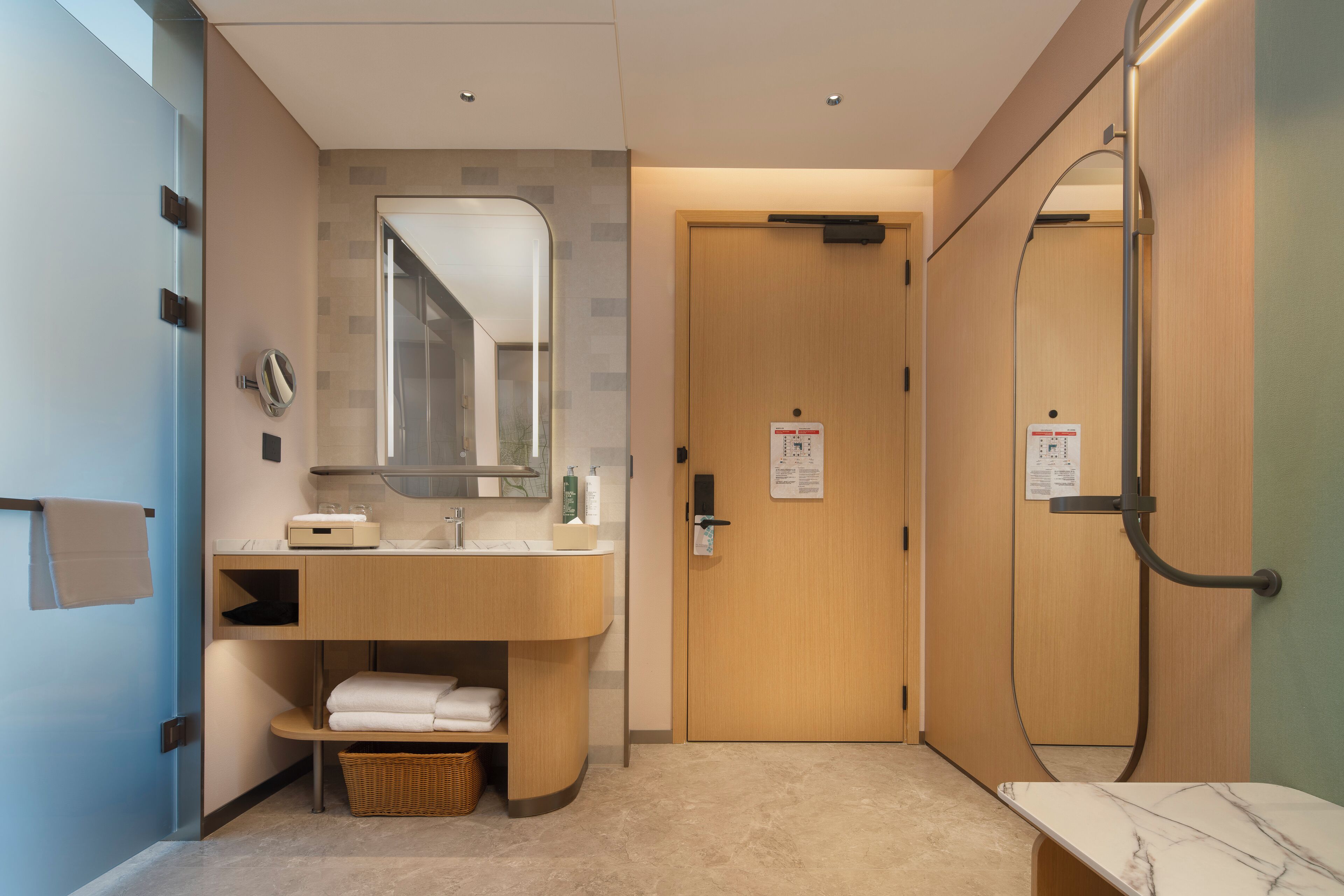 A modern bathroom with a wooden vanity, a mirror, a shower, and a towel rack.