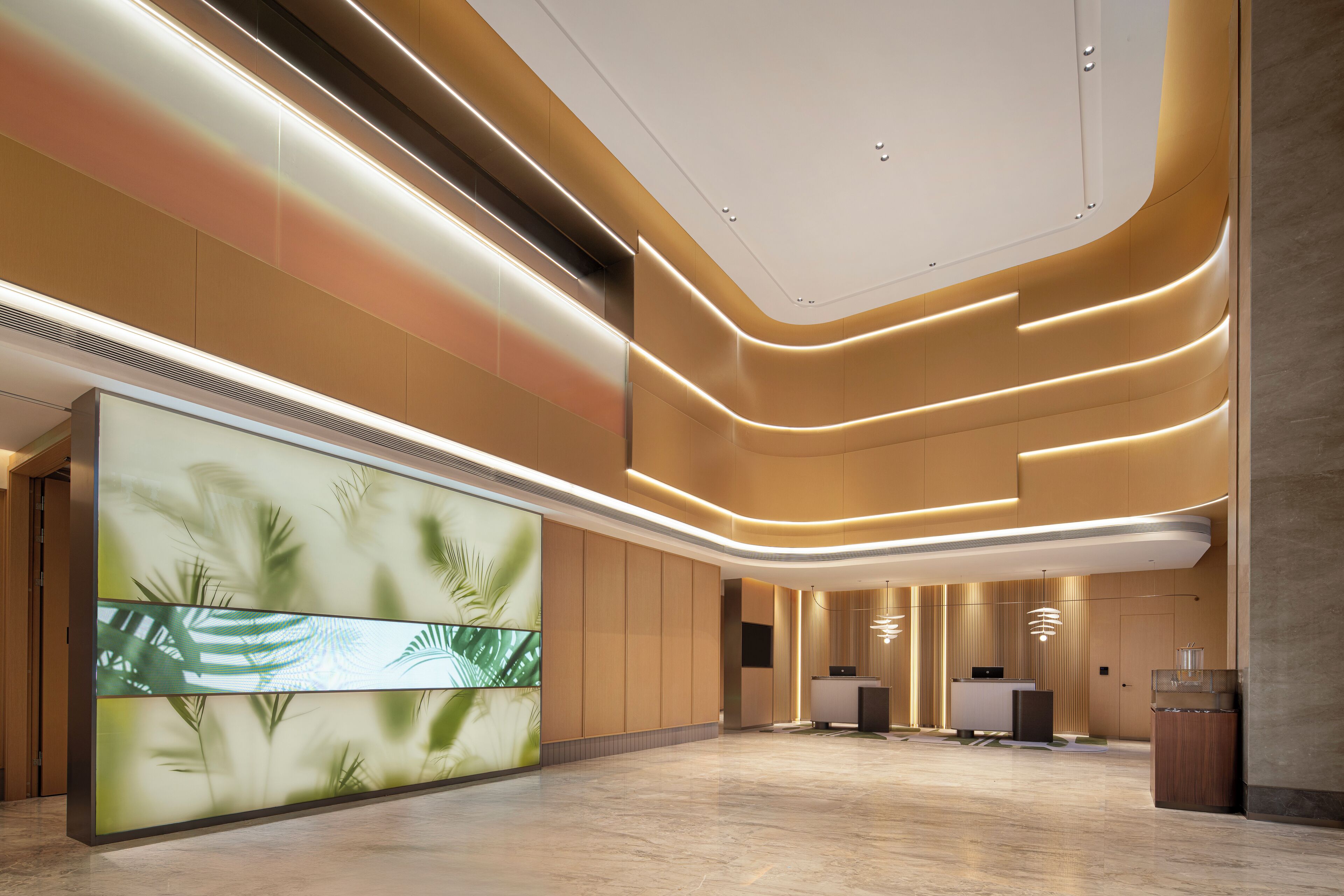 Una hall moderna di un hotel, con una reception, un grande schermo digitale e un soffitto dalle linee curve.