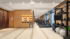 Un gimnasio moderno con cintas de correr, pesas y un reloj de pared.