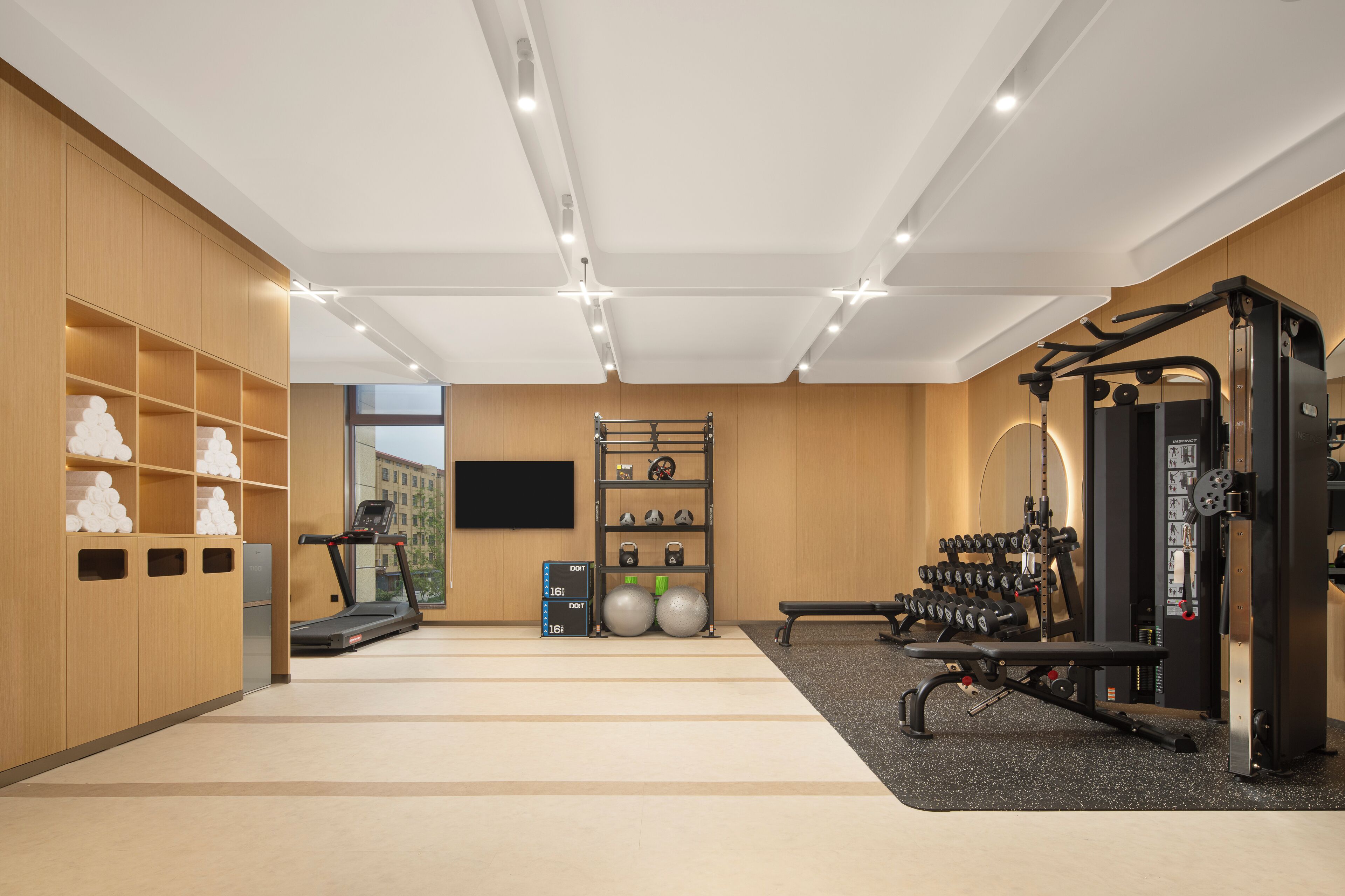 A gym with exercise equipment, a treadmill, and a wall-mounted TV.