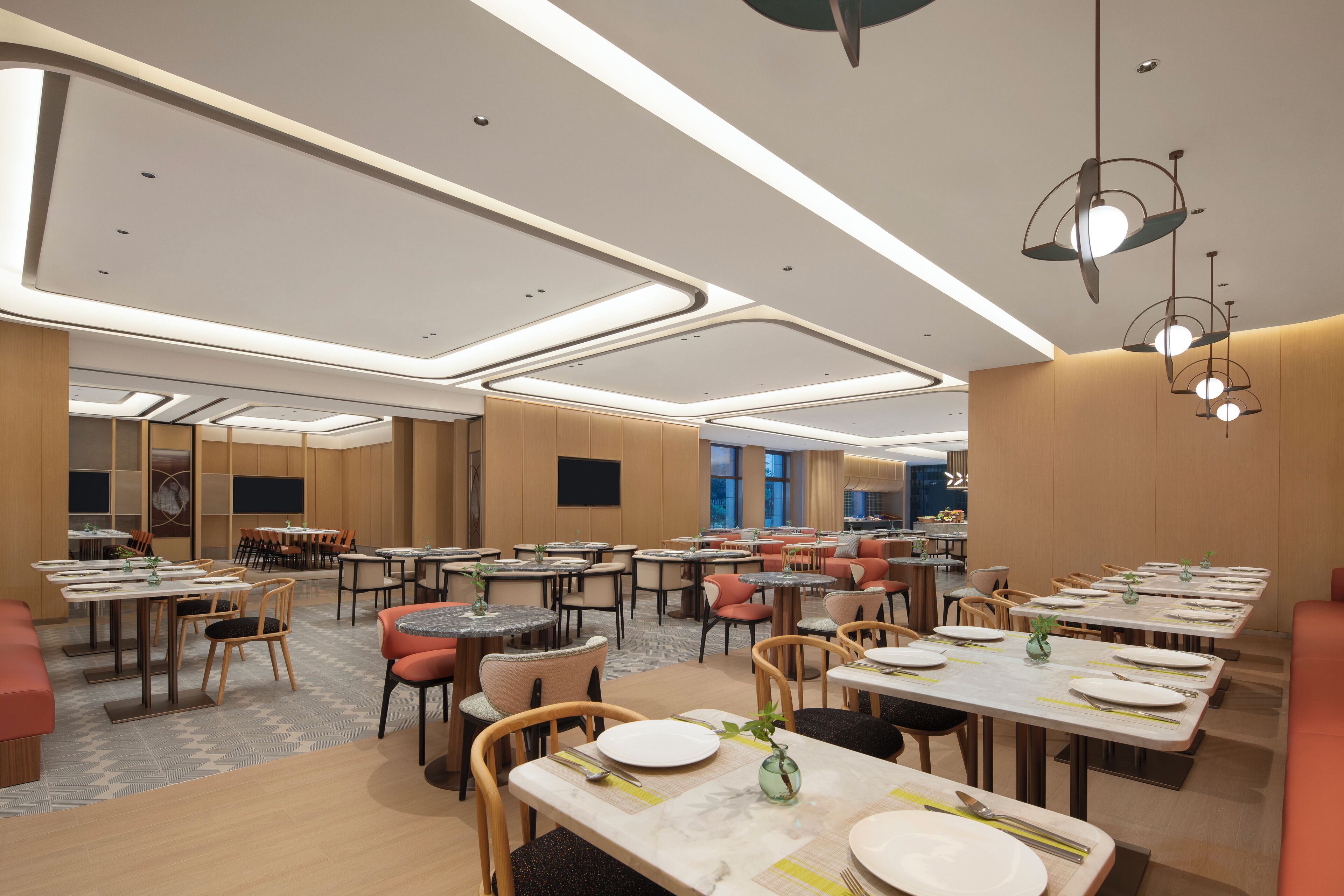 A spacious dining area with multiple tables and chairs, modern lighting fixtures, and a clean, contemporary design.