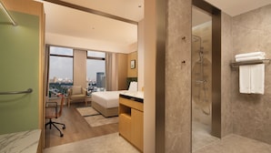 A modern hotel room with a city view, a bed, a desk, a shower, and a bathroom. - Hilton Garden Inn Linyi Shangcheng (Linyi)