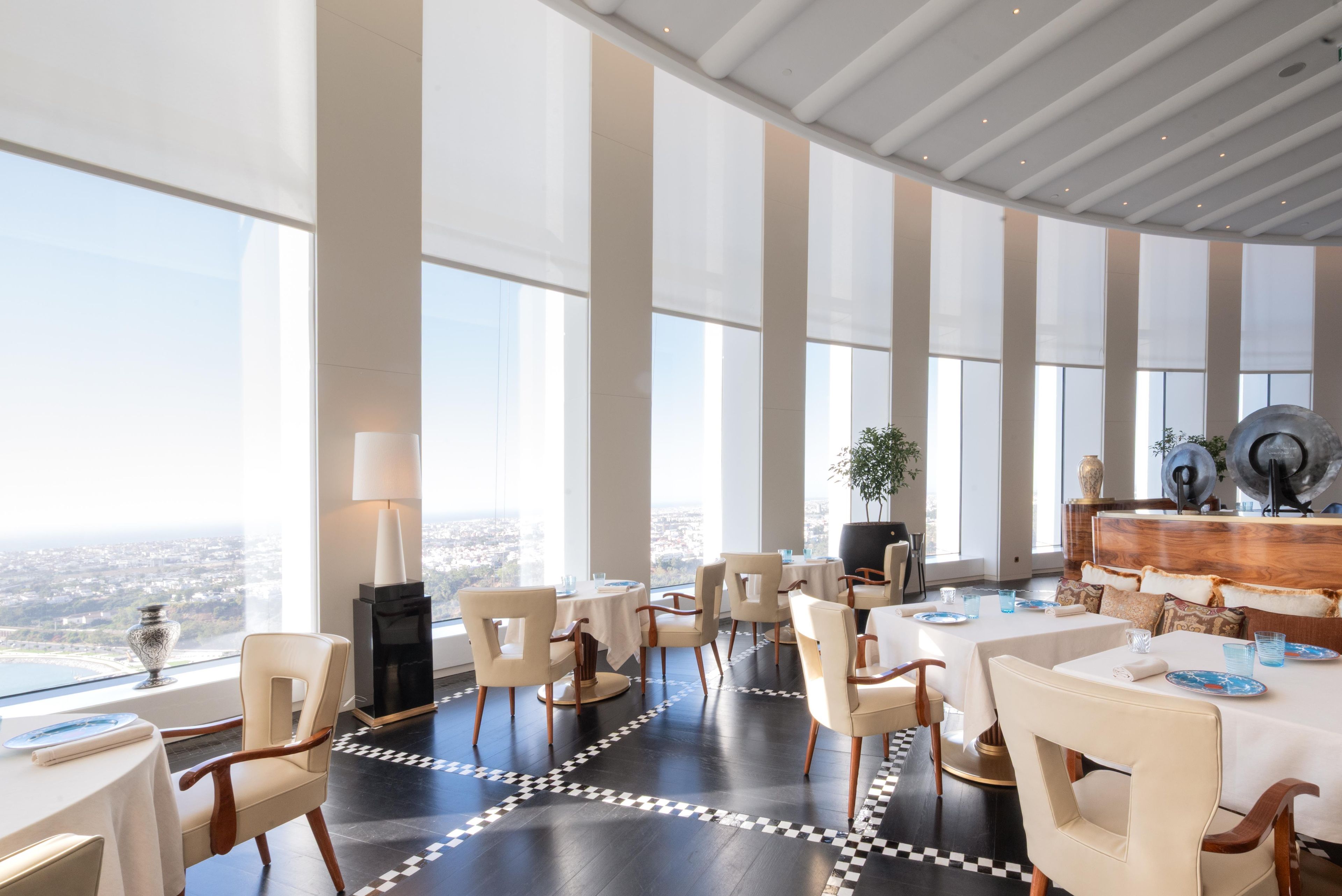 A spacious dining area with high ceilings and large windows offering a city view.