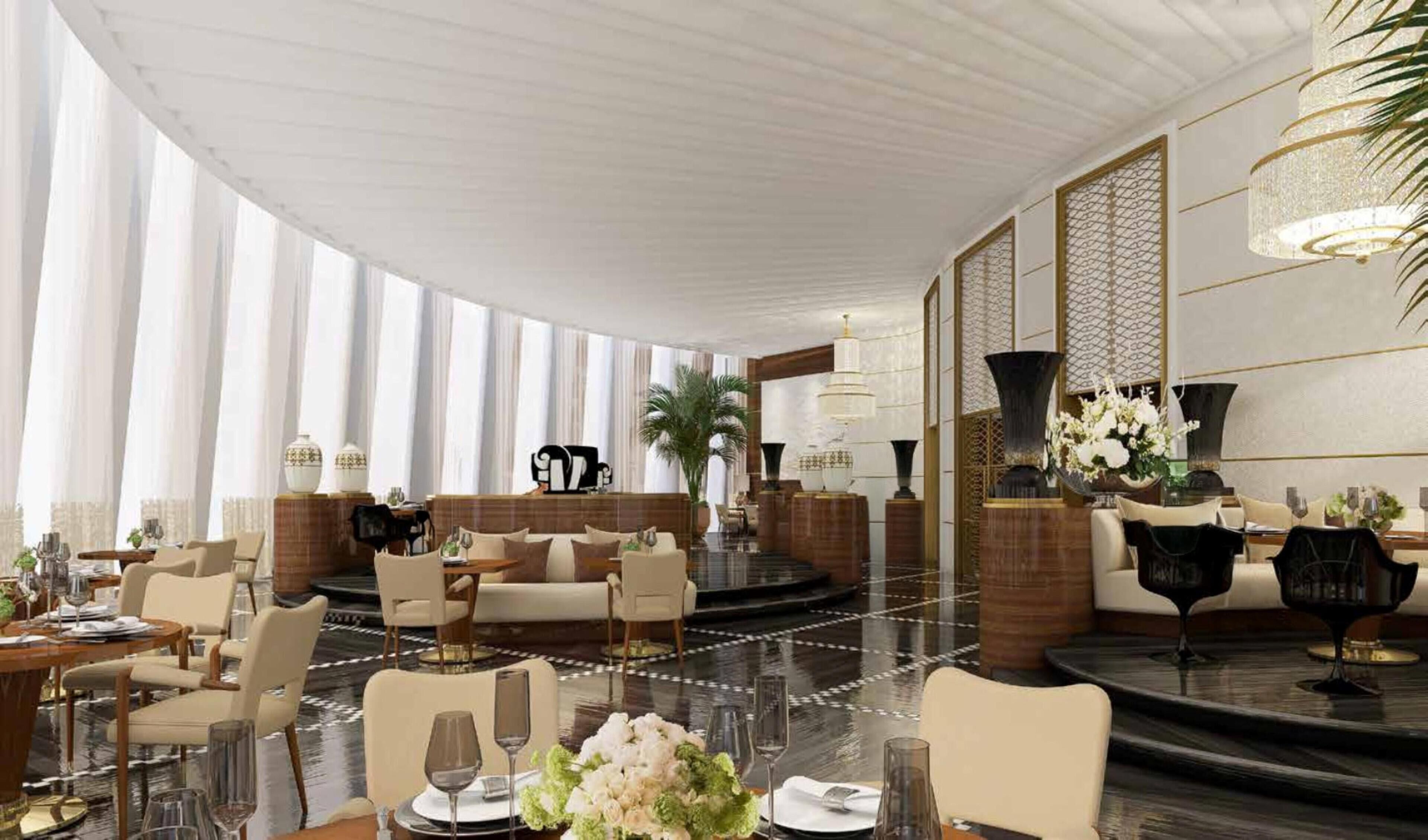 A spacious hotel lobby with a high ceiling, large windows, and a central seating area with sofas and chairs.