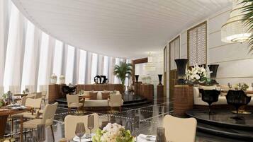 A spacious hotel lobby with a high ceiling, large windows, and a central seating area with sofas and chairs.