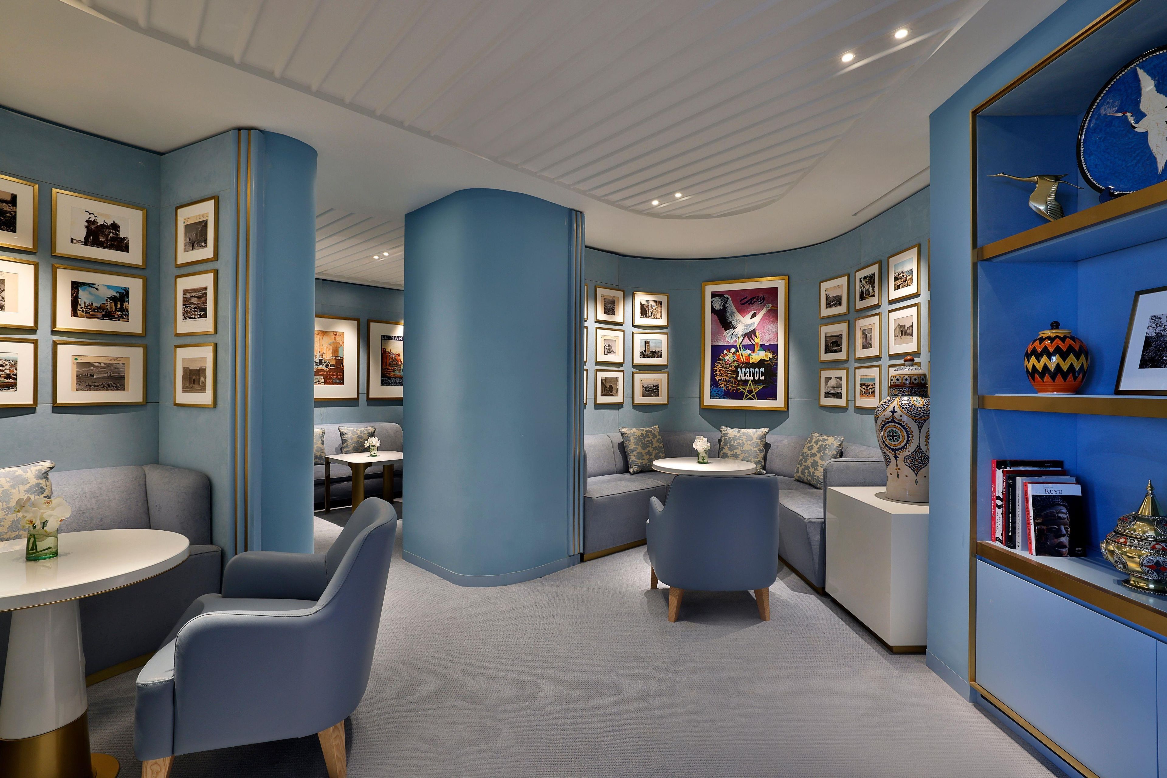 A modern interior with a curved ceiling, blue walls, and a bookshelf with framed pictures.