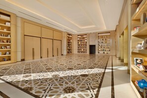 A spacious room with a geometric patterned floor, built-in shelving with various items, and a modern ceiling design. - Waldorf Astoria Rabat Salé (Salé)