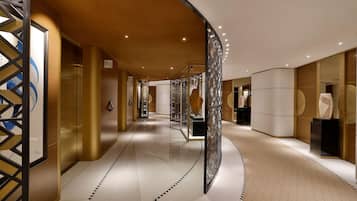 Un pasillo moderno de hotel con techo curvo, paredes con diseño y suelo de baldosas.