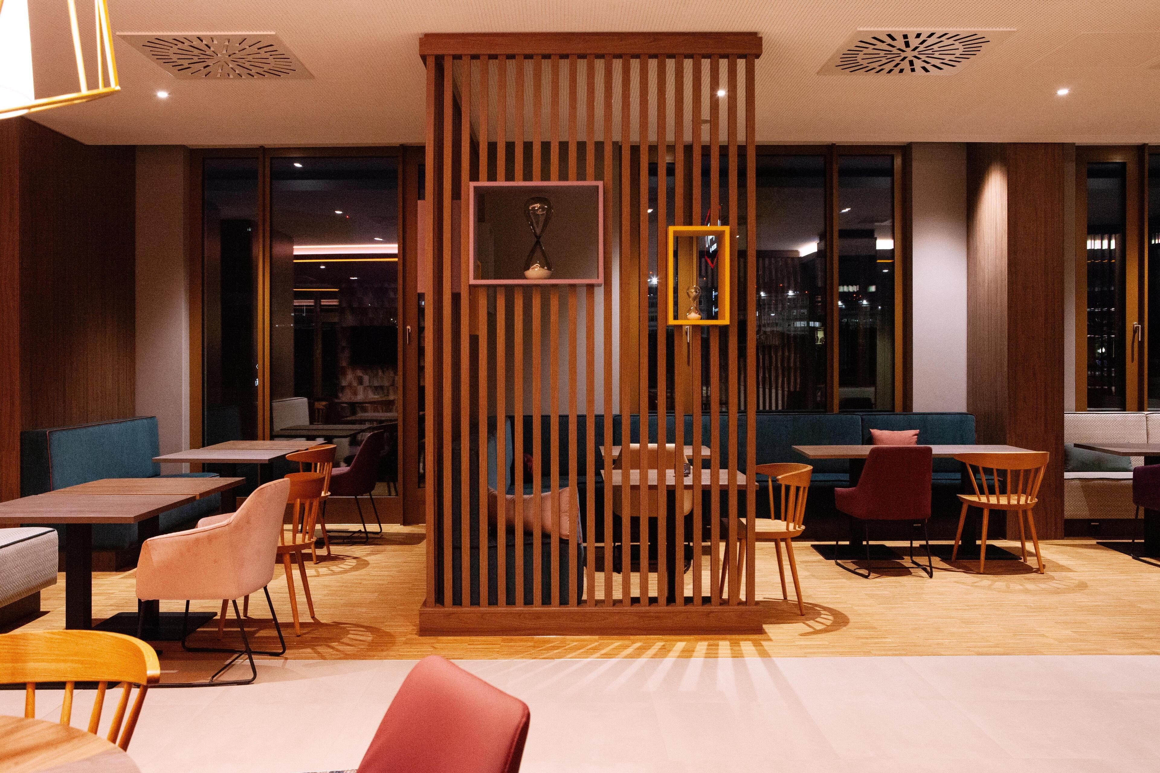 A modern restaurant with wooden partitions, tables, and chairs.
