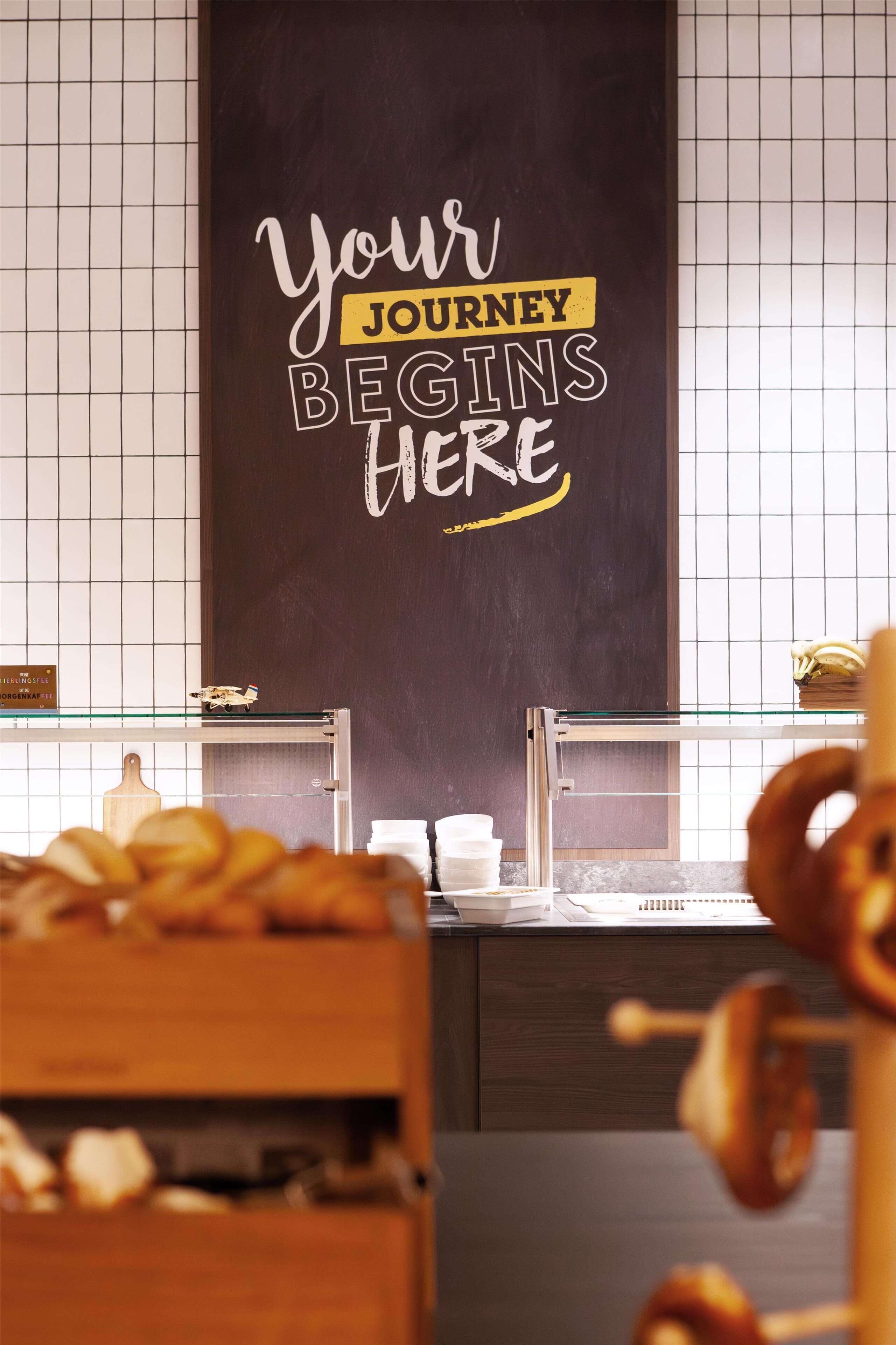 A bakery counter with a chalkboard sign that reads "Your Journey Begins Here."
