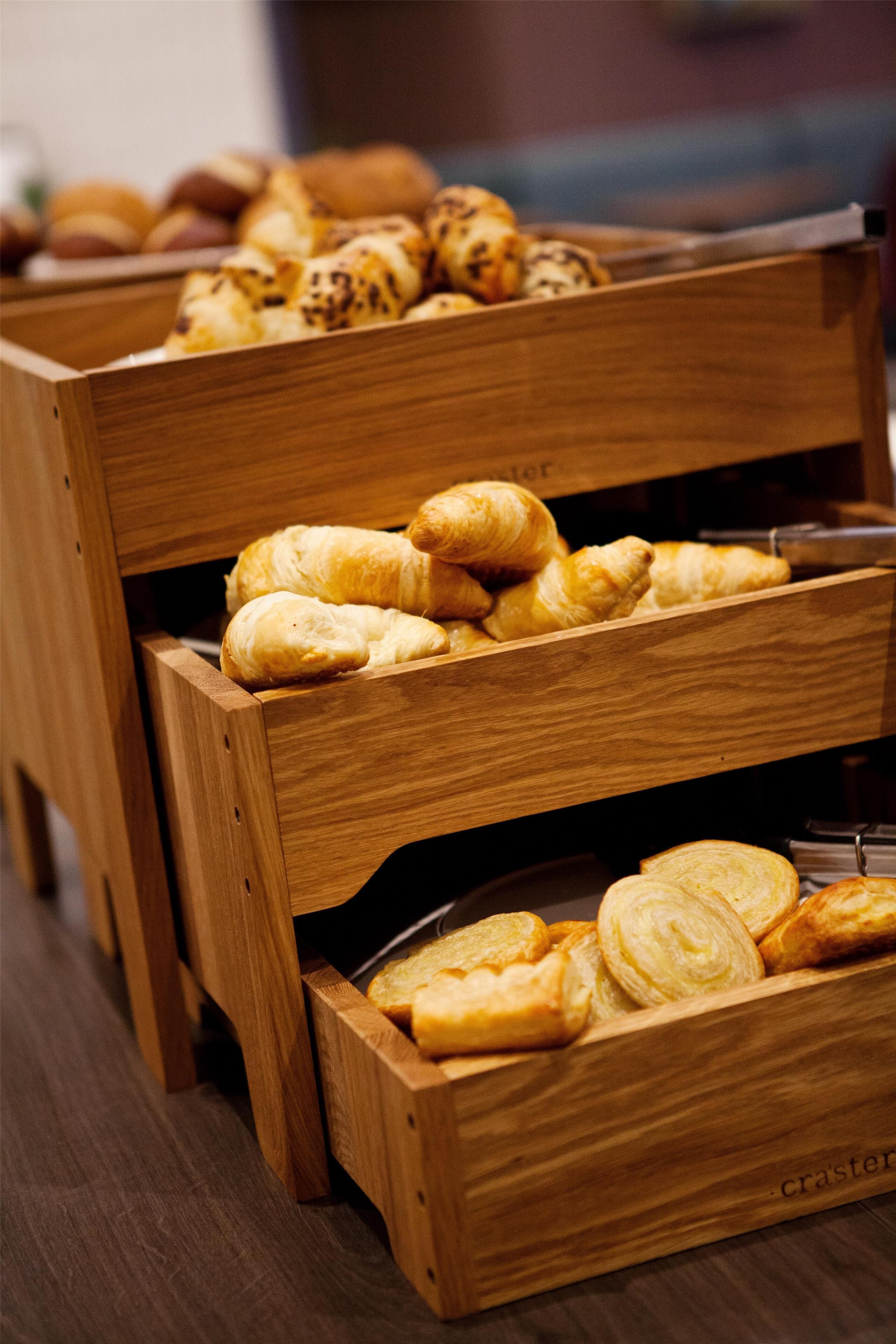 Eine Holzeinlage mit verschiedenen Backwaren, darunter Croissants und Gebäck.