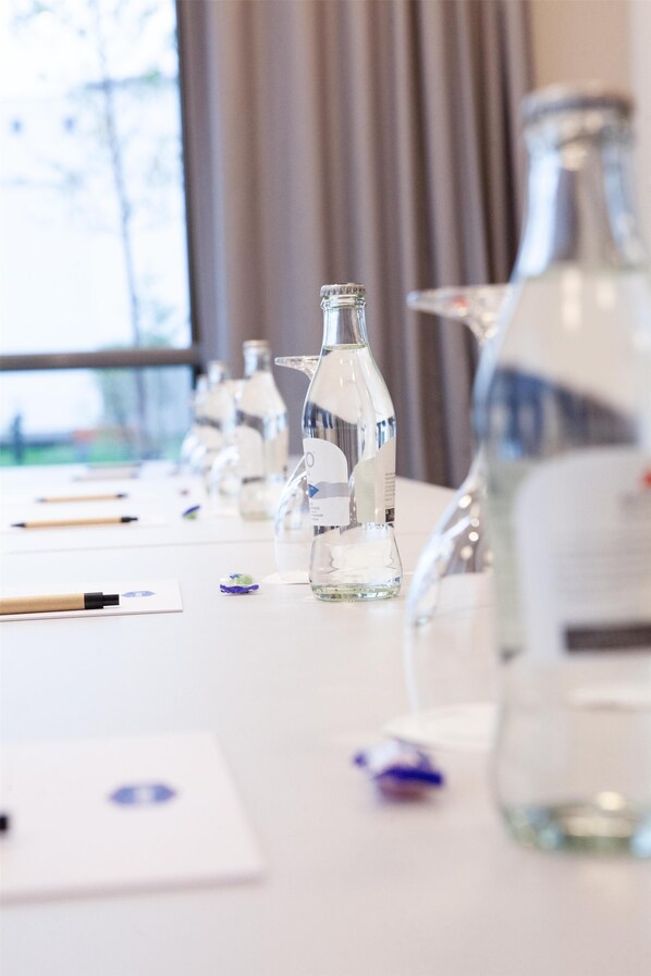 A conference table with several clear glass bottles, some with labels, and a few pens on a white surface. - Hampton By Hilton Stuttgart Airport (Filderstadt)