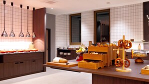 Una cucina moderna con mobili in legno, un'isola centrale con pane e brezel, e lampade a sospensione.