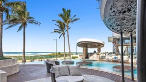 A pool area with lounge chairs, a bar, and a view of the ocean. - Luxe Absolute beachfront 2B River and Sunset views/Spa/Sauna/Steam/Free parking! (Surfers Paradise)