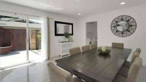 Un comedor moderno con una mesa grande, sillas, un espejo y un elemento decorativo en la pared.