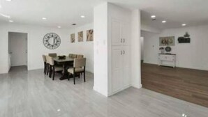 Una habitación amplia con comedor, un armario blanco y suelo de madera.