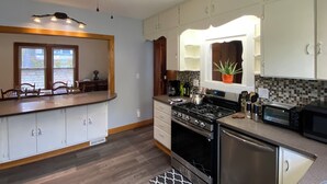 A kitchen with white cabinets, a black stove, a microwave, and a ceiling fan.
