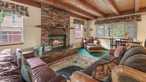 A cozy living room with a brick fireplace, leather sofas, and a dining area with a table and chairs.