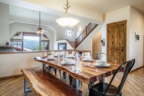 A dining area with a wooden table set for four, a bench, and a staircase leading to another level.