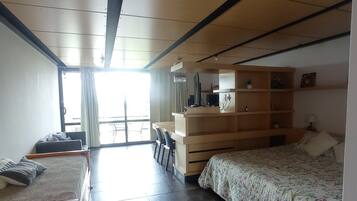 Un dormitorio con cama, escritorio, silla, armario y ventana.