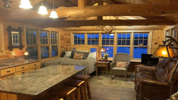 L’intérieur d’un chalet confortable en bois, comprenant une cuisine, un coin repas et un espace salon.