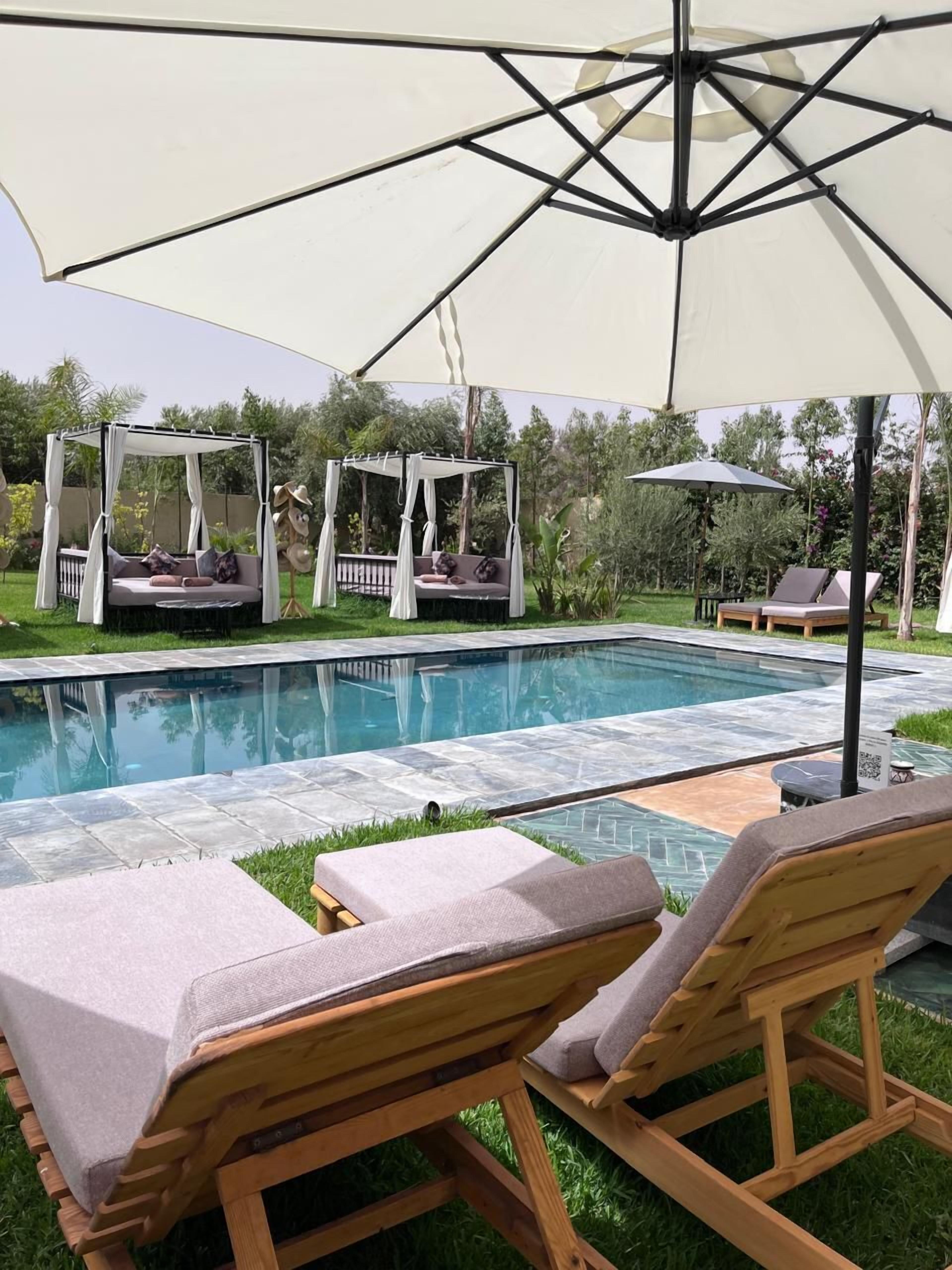 A poolside area with a canopy, lounge chairs, and a small table.
