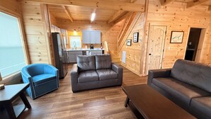A wooden interior with a sofa, a blue chair, and a dining area. - Brand new cabin with HOT TUB, Dock & Lake Access (Butler)