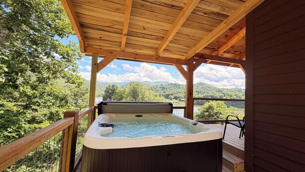 A hot tub on a wooden deck with a view of mountains and trees. - Brand new cabin with HOT TUB, Dock & Lake Access (Butler)