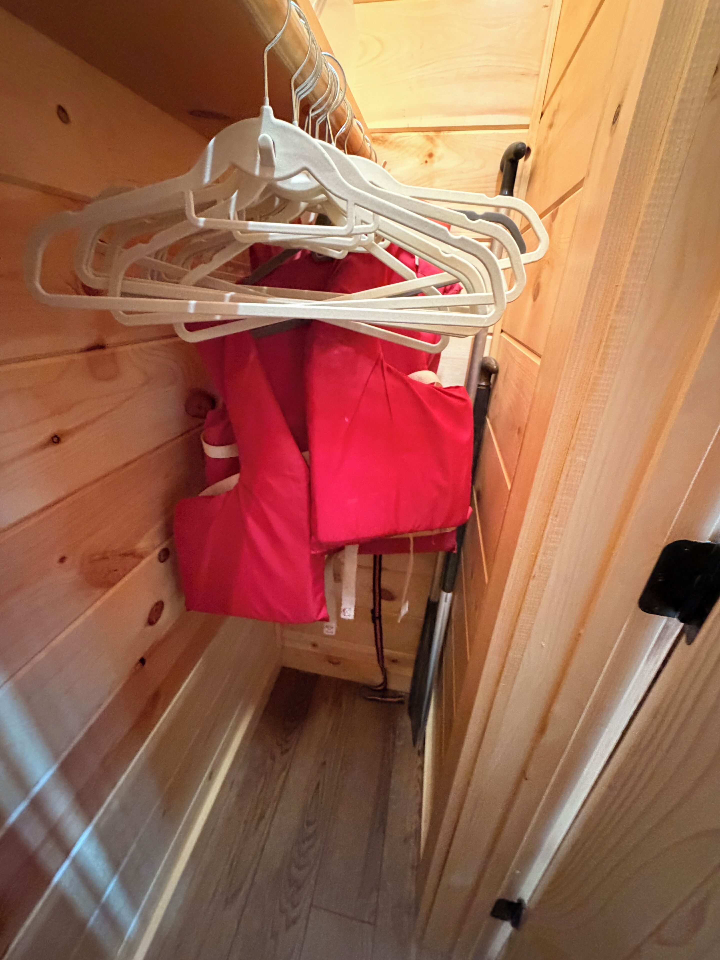 Une petite pièce étroite en bois, avec un lit, un radiateur blanc et une porte en bois.