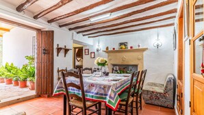 A dining area with a table set for four, wooden chairs, a tiled floor, and a fireplace with a mantel. - Lovely home in Archidona with private swimming pool, can be inside or outside (Archidona)