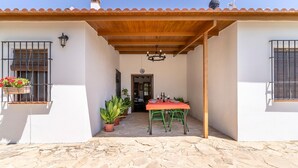 A patio with a stone floor, a wooden pergola, a table with chairs, and potted plants. - Lovely home in Archidona with private swimming pool, can be inside or outside (Archidona)