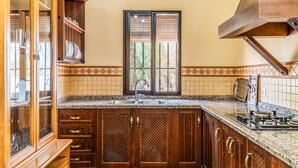 A kitchen with wooden cabinets, a granite countertop, a double sink, and a window with blinds. - Lovely home in Archidona with private swimming pool, can be inside or outside (Archidona)