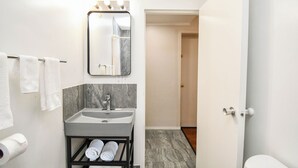 Un baño moderno con lavamanos, espejo y perchero para toallas.
